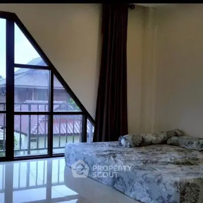 Spacious bedroom with large windows and modern decor, offering natural light and serene views.