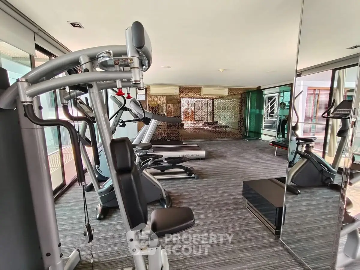 Modern gym with state-of-the-art equipment and mirrored walls in luxury apartment complex.