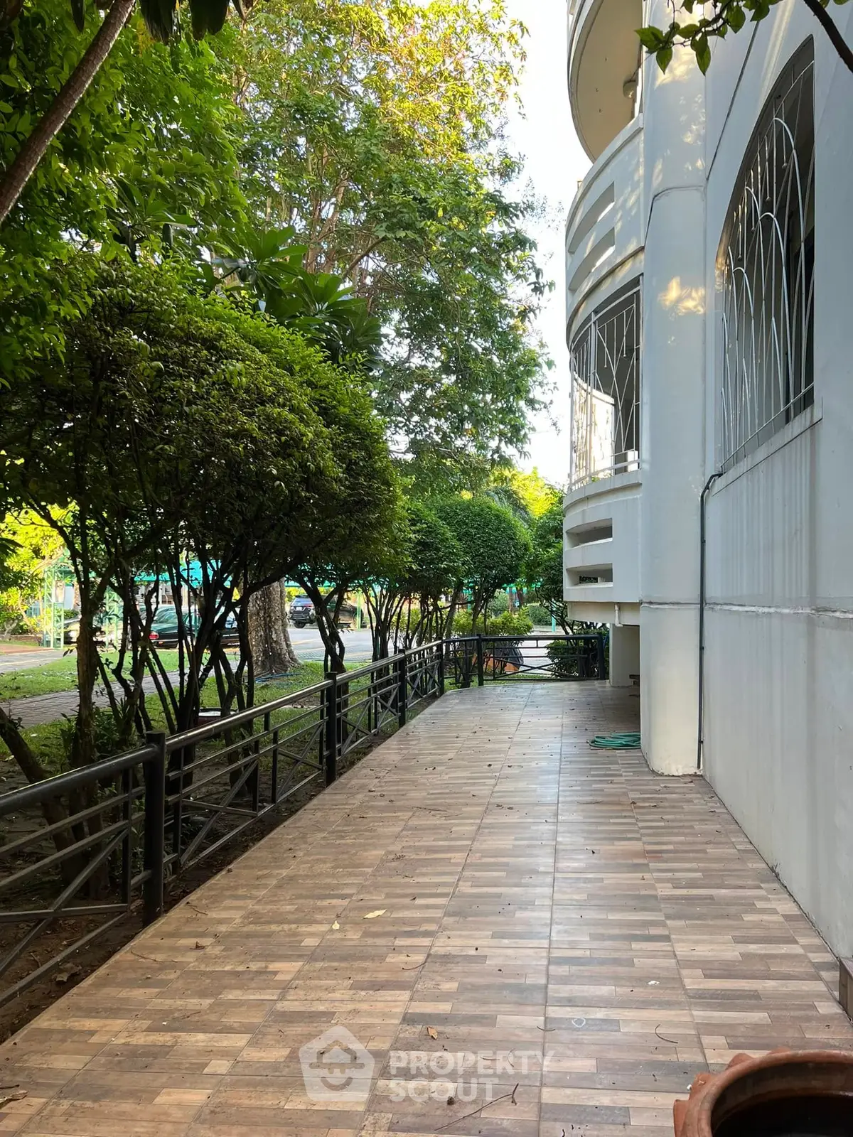 Charming building exterior with lush greenery and tiled pathway