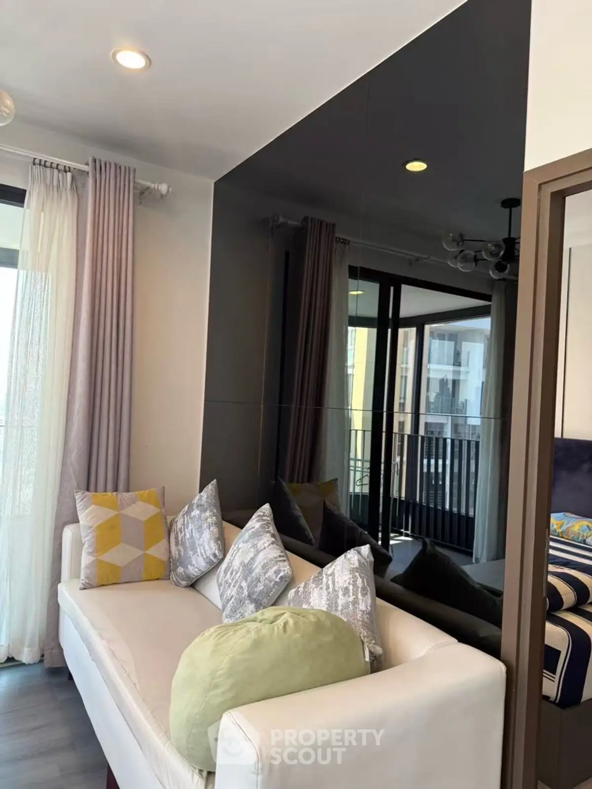 Modern living room with stylish sofa and large windows offering natural light and city views.