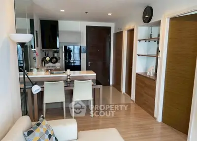 Modern open-plan living room with stylish kitchen and dining area, featuring sleek wooden finishes and contemporary decor.
