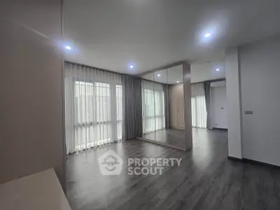 Spacious modern room with large windows and mirrored wall, perfect for stylish living.
