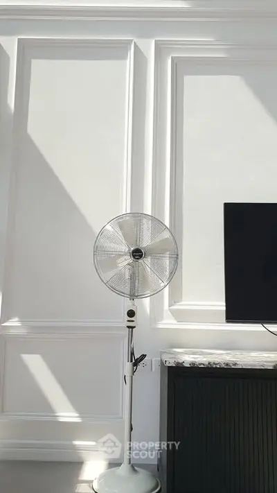 Elegant interior with modern fan and sleek TV setup, showcasing minimalist design and natural light.