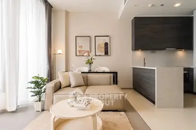 Modern living room with open kitchen, stylish decor, and natural light.