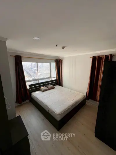 Spacious bedroom with city view and modern furnishings in high-rise apartment