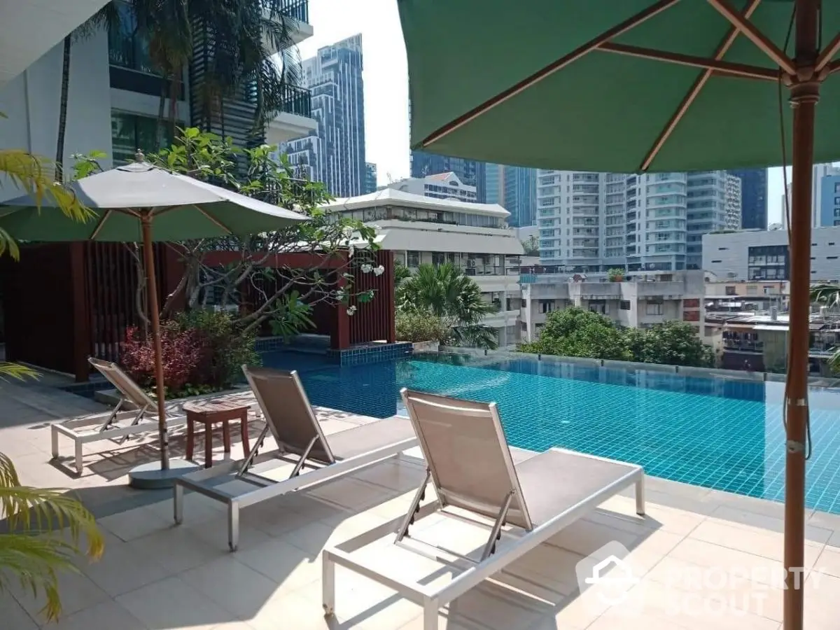 Luxurious rooftop pool with city skyline view and sun loungers in modern apartment complex.