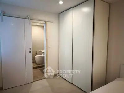 Modern bedroom with sliding door leading to a sleek bathroom