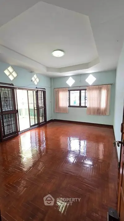 Spacious living room with polished wooden floors and large windows for natural light.