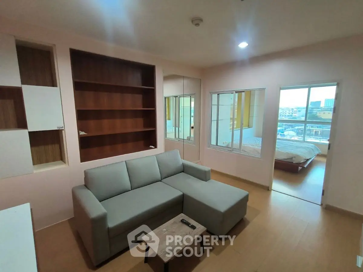 Modern living room with cozy sofa and open view to bedroom and balcony.