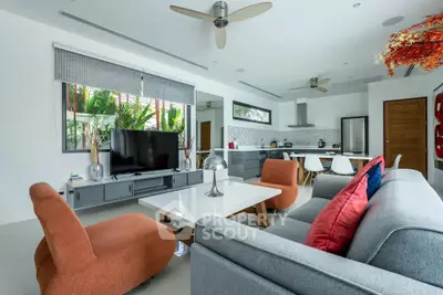 Modern open-plan living room with stylish decor and kitchen area, featuring large windows and contemporary furniture.