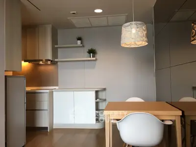 Modern kitchen with sleek cabinets and dining area featuring stylish lighting.