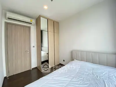 Modern bedroom with sleek wardrobe and air conditioning in a stylish apartment.