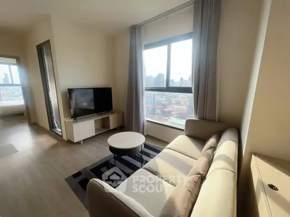 Modern living room with city view, cozy sofa, and flat-screen TV in a bright apartment.