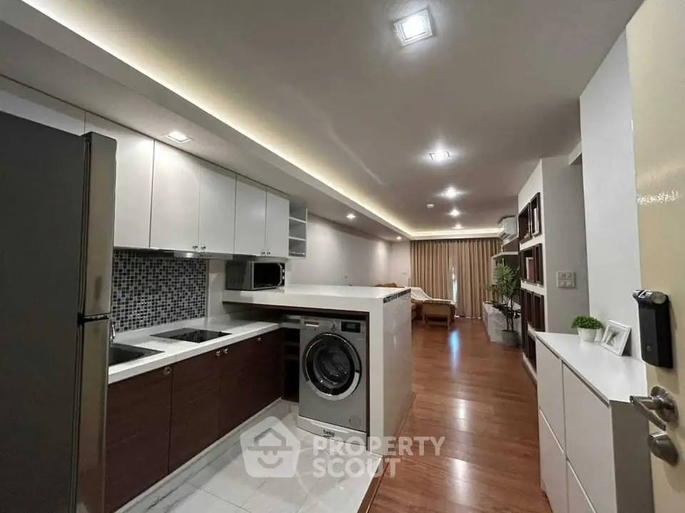 Modern open-layout kitchen with sleek appliances and stylish living area in a contemporary apartment.