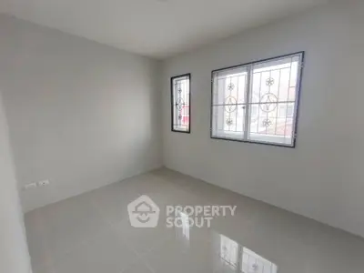 Spacious empty room with tiled flooring and large windows in modern home.