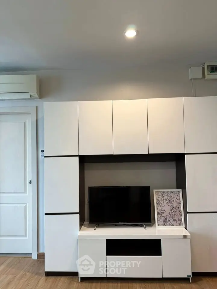 Modern living room with sleek white cabinetry and mounted TV, showcasing minimalist design.