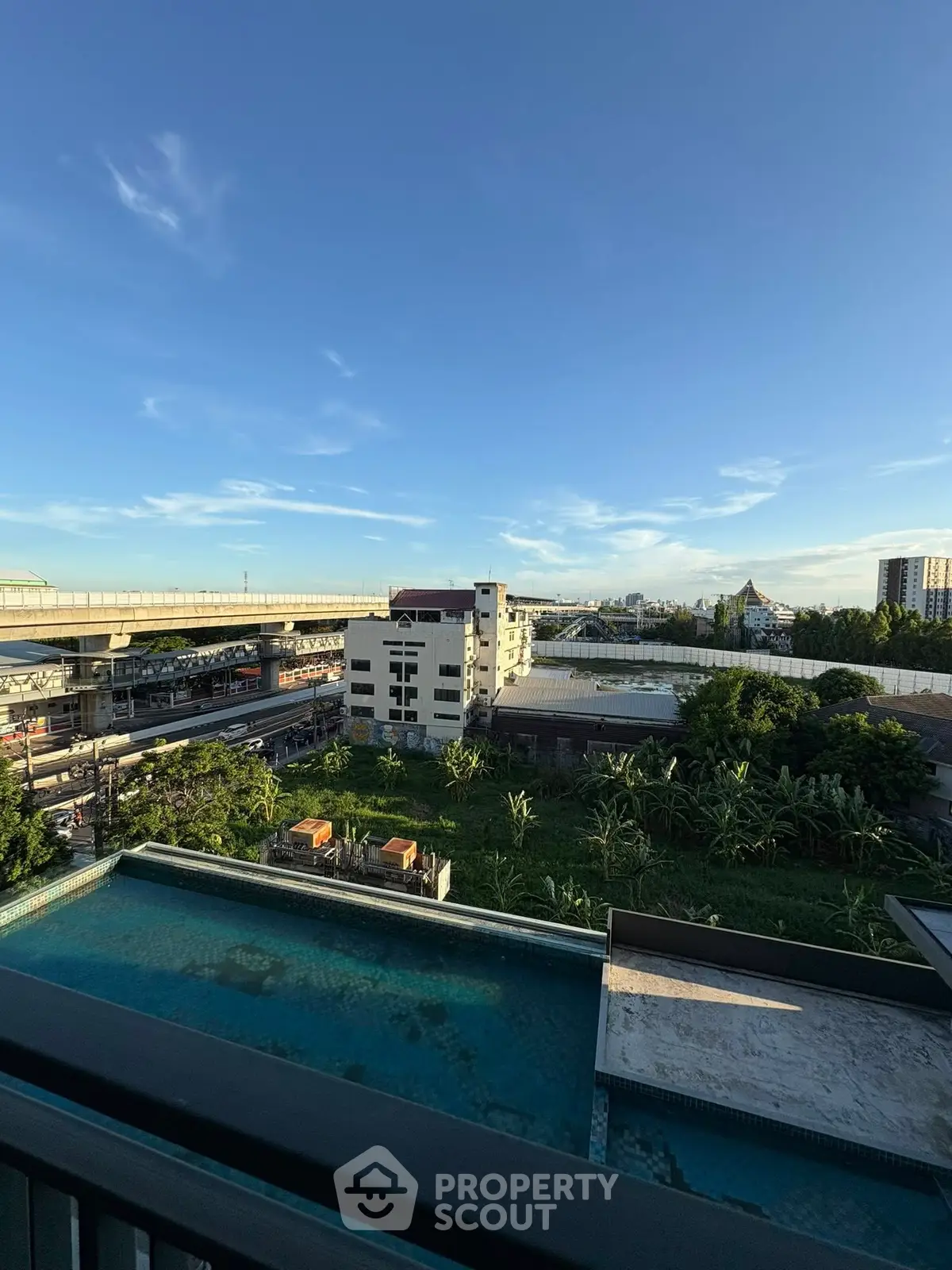 Stunning cityscape view from a high-rise balcony overlooking urban skyline and lush greenery.