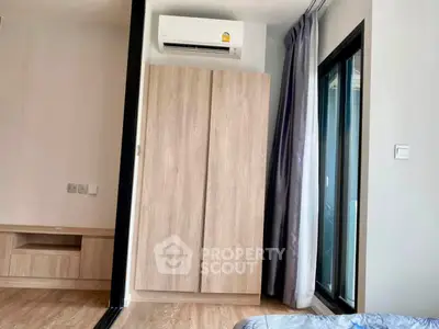 Modern bedroom with air conditioning and large wardrobe, featuring a sliding glass door to a balcony.
