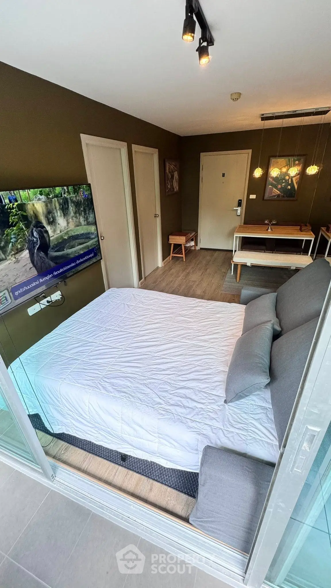 Modern bedroom with glass wall, stylish decor, and wall-mounted TV in a cozy apartment.