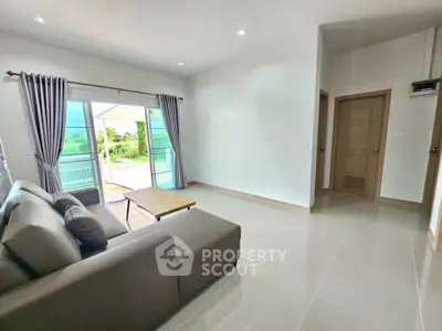 Spacious living room with modern sofa and large windows opening to a scenic view.
