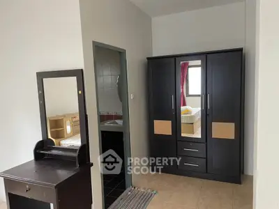 Cozy bedroom with wardrobe and vanity, adjacent to a bathroom.