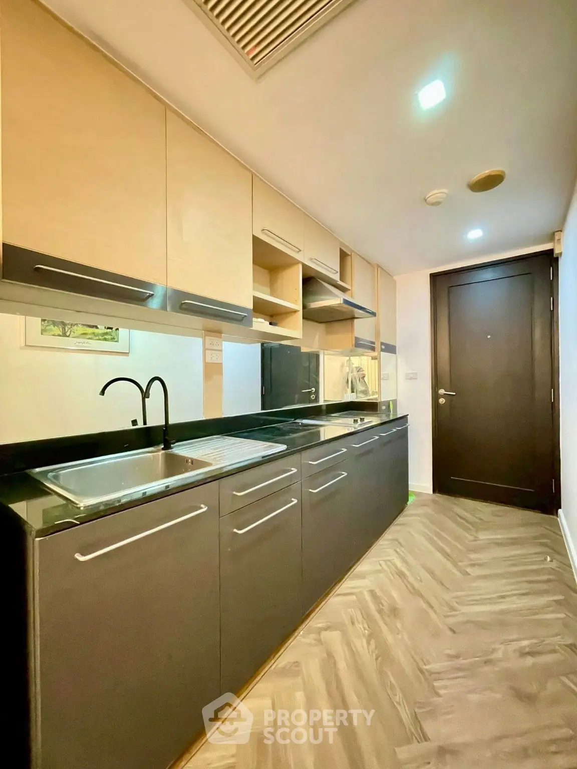 Modern kitchen with sleek cabinetry and black countertops in a stylish apartment.