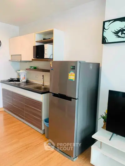 Modern kitchen with sleek appliances and stylish cabinetry in a cozy apartment setting.