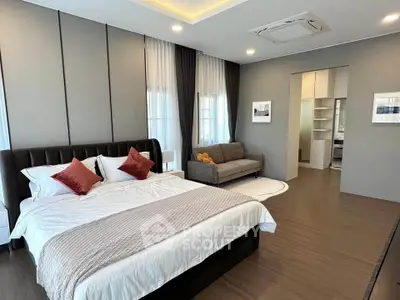 Spacious modern bedroom with elegant decor and cozy seating area.