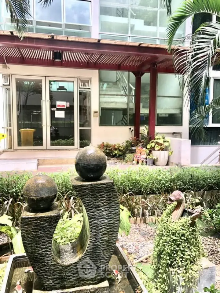 Charming building entrance with modern sculpture and lush greenery