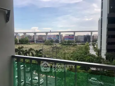 Scenic balcony view overlooking urban landscape with greenery and distant buildings.
