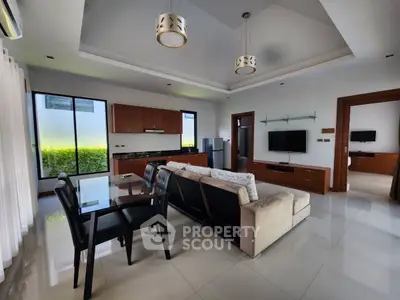 Spacious modern living room with open kitchen, stylish decor, and natural light.