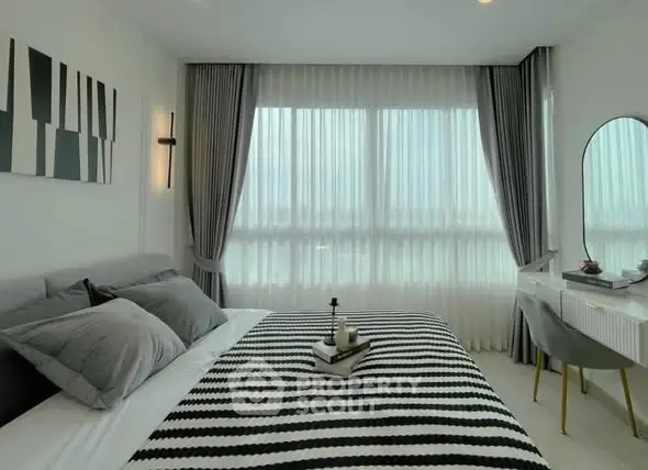 Modern bedroom with stylish decor and large window offering natural light.