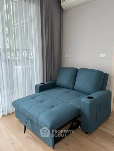 Modern living room with stylish blue sofa bed and large window for natural light.