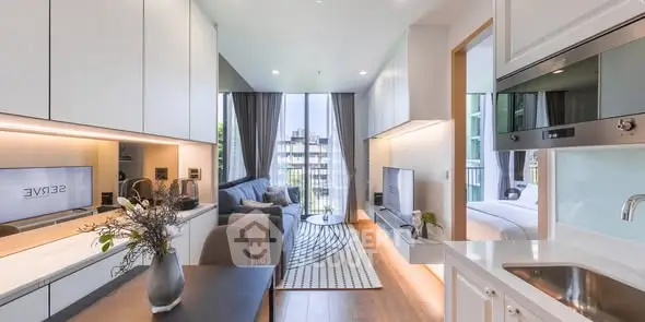 Modern open-plan living room with sleek kitchen and large windows offering natural light.