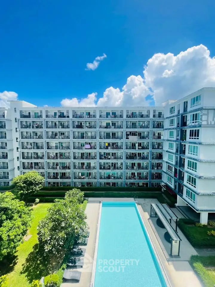 Modern condominium with pool and lush garden under a bright blue sky.