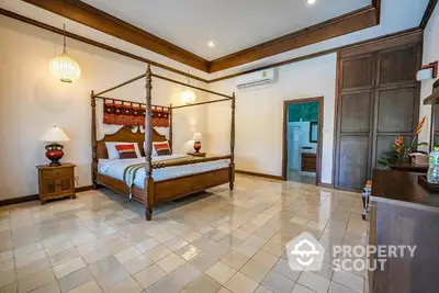 Spacious bedroom with polished tile flooring, a grand four-poster bed, and traditional wooden furniture creating a luxurious tropical ambiance.