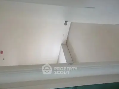 Minimalist interior with white walls and ceiling light fixture.