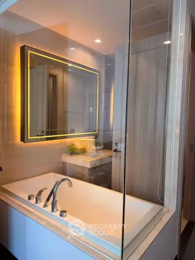 Luxurious bathroom with modern bathtub and illuminated mirror in elegant real estate property.