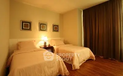 Cozy twin bedroom with warm lighting and elegant decor, perfect for relaxation.