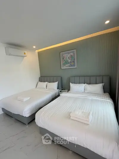 Spacious bedroom with two comfortable beds and modern decor, perfect for relaxation.