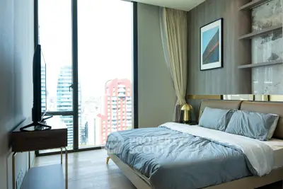 Modern bedroom with city view, stylish decor, and large window for natural light.