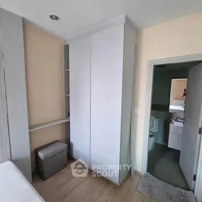 Modern bedroom with built-in wardrobe and ensuite bathroom, featuring sleek design and neutral tones.
