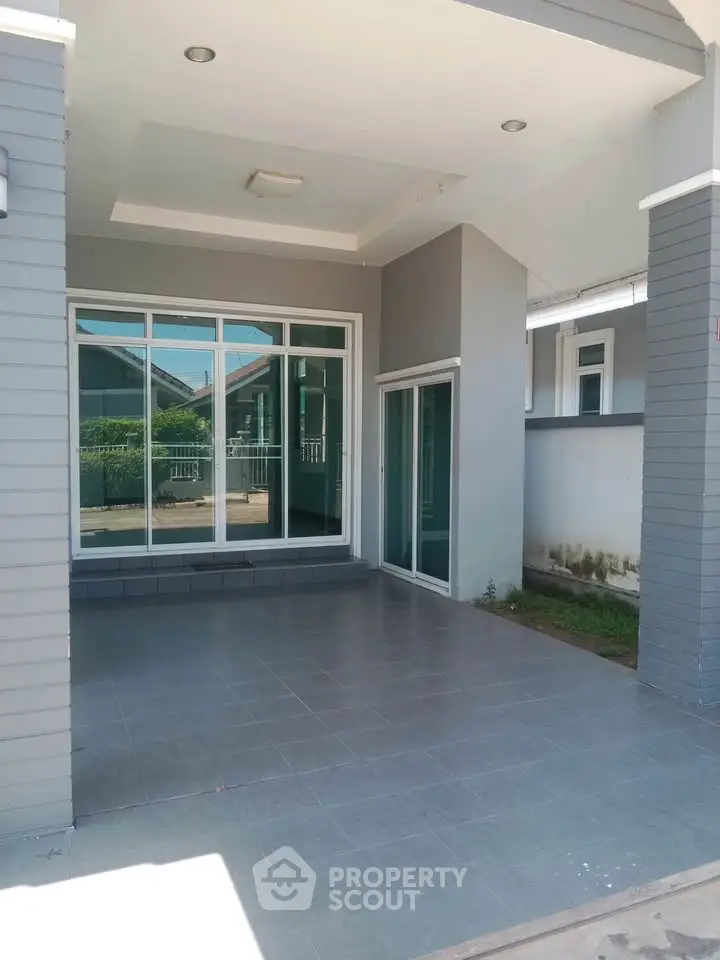 Modern house entrance with large windows and tiled patio