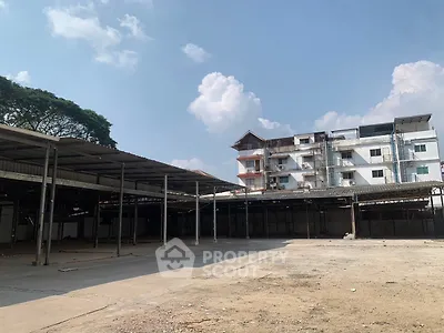 Spacious open industrial area with adjacent building under clear blue sky.