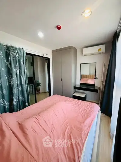 Cozy bedroom with pink bedding, mirrored vanity, and air conditioning