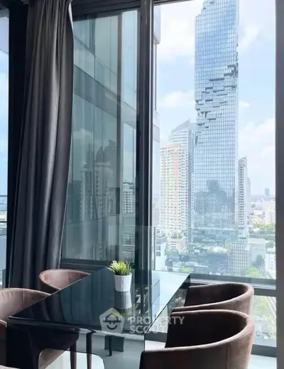 Stunning city view from modern high-rise apartment with sleek glass table and plush chairs.