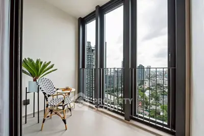 Stylish balcony with city view, modern seating, and lush plant for urban living.