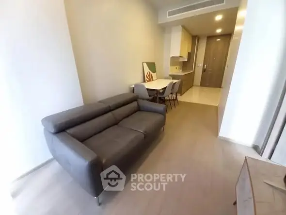 Modern apartment interior with sleek sofa and dining area, showcasing open layout and stylish design.