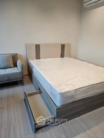 Modern bedroom with stylish bed and cozy armchair, featuring sleek wooden flooring and neutral tones.