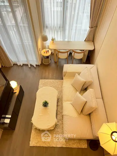 Spacious modern living room with high ceilings and elegant decor, featuring a cozy sofa and large windows.